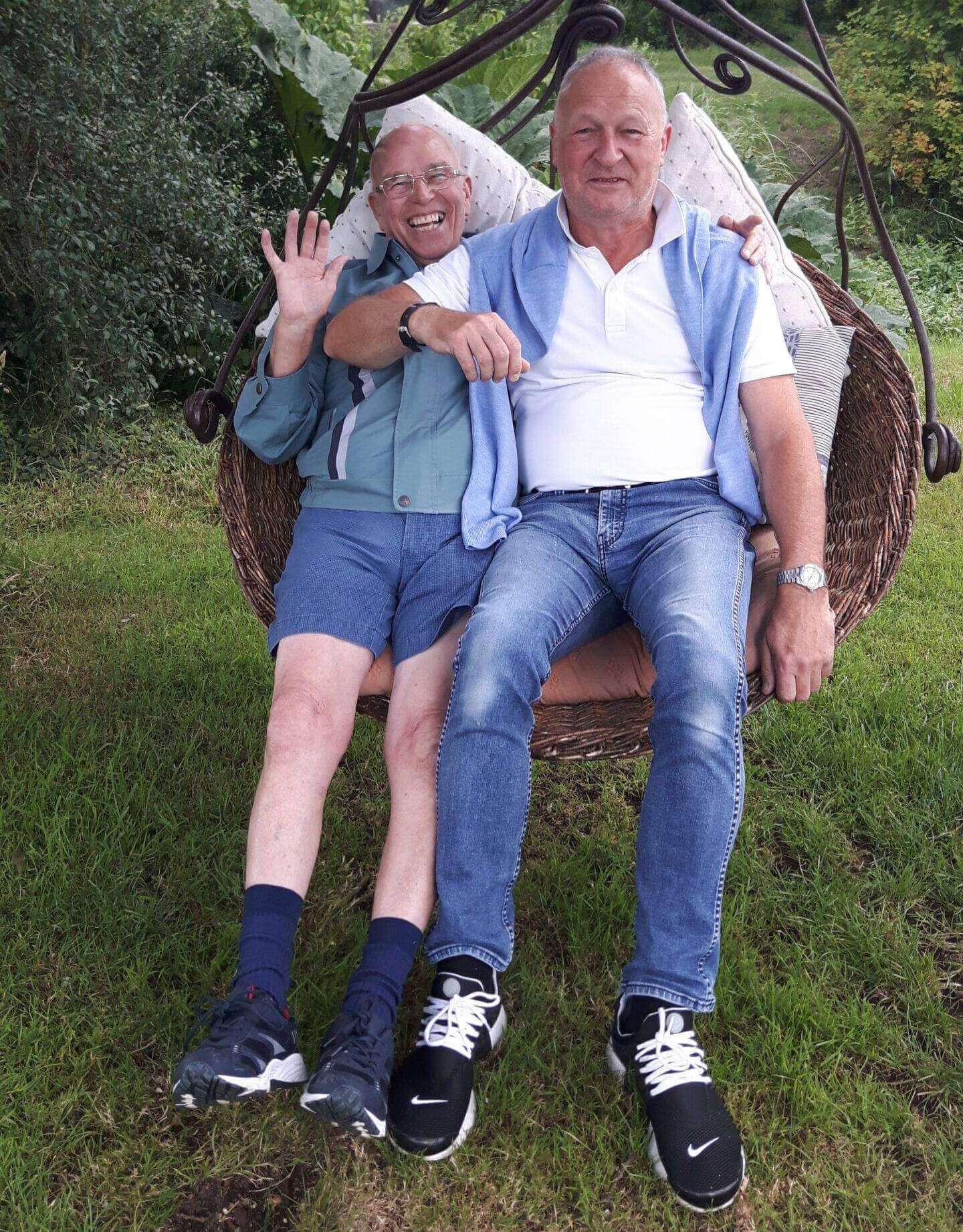 Two men with dementia sat on a swing.